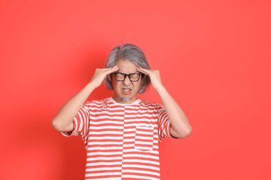 Turuncu arka planda günlük giysileri olan kıdemli Asyalı adam..