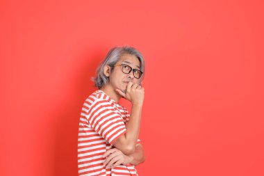 Turuncu arka planda günlük giysileri olan kıdemli Asyalı adam..