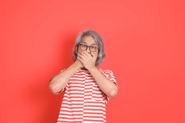 Turuncu arka planda günlük giysileri olan kıdemli Asyalı adam..