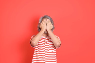 Turuncu arka planda günlük giysileri olan kıdemli Asyalı adam..