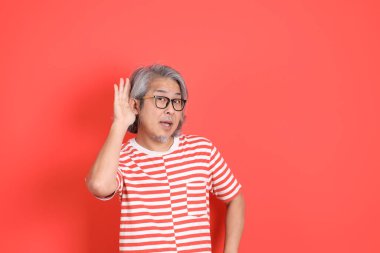 Turuncu arka planda günlük giysileri olan kıdemli Asyalı adam..