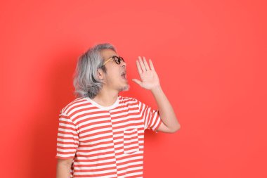 Turuncu arka planda günlük giysileri olan kıdemli Asyalı adam..