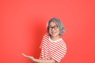 Turuncu arka planda günlük giysileri olan kıdemli Asyalı adam..