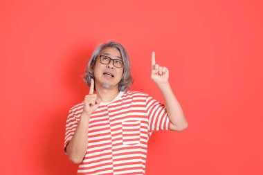 Turuncu arka planda günlük giysileri olan kıdemli Asyalı adam..