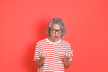 Turuncu arka planda günlük giysileri olan kıdemli Asyalı adam..