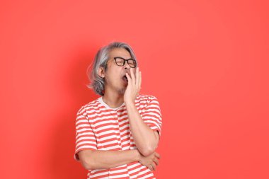 Turuncu arka planda günlük giysileri olan kıdemli Asyalı adam..