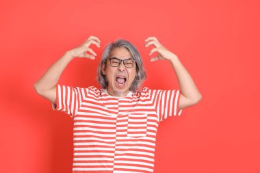 Turuncu arka planda günlük giysileri olan kıdemli Asyalı adam..