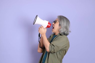 Mor arka planda dikilen sıradan giysili kıdemli Asyalı adam..