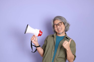 Mor arka planda dikilen sıradan giysili kıdemli Asyalı adam..