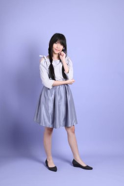 Mor arka planda duran mor giysili Asyalı genç kız..