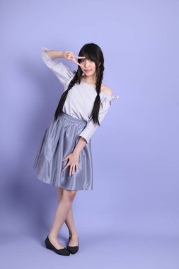 Mor arka planda duran mor giysili Asyalı genç kız..