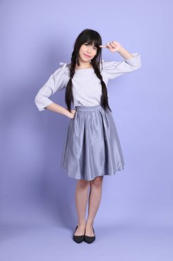 Mor arka planda duran mor giysili Asyalı genç kız..