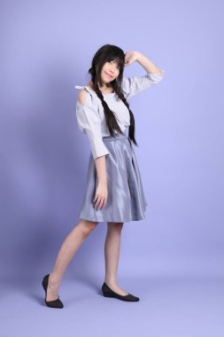 Mor arka planda duran mor giysili Asyalı genç kız..