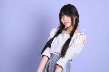 Mor arka planda duran mor giysili Asyalı genç kız..