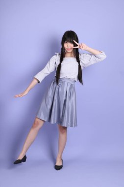 Mor arka planda duran mor giysili Asyalı genç kız..