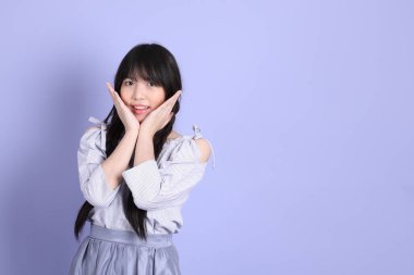 Mor arka planda duran mor giysili Asyalı genç kız..