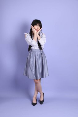 Mor arka planda duran mor giysili Asyalı genç kız..