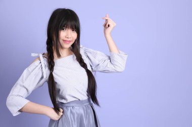 Mor arka planda duran mor giysili Asyalı genç kız..