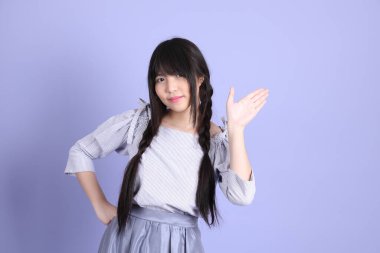 Mor arka planda duran mor giysili Asyalı genç kız..