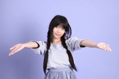 Mor arka planda duran mor giysili Asyalı genç kız..