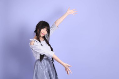 Mor arka planda duran mor giysili Asyalı genç kız..