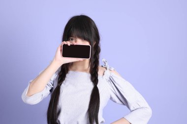 Mor arka planda duran mor giysili Asyalı genç kız..