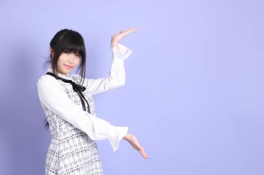 Mor arka planda duran beyaz elbiseli Asyalı genç kız..