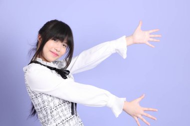 Mor arka planda duran beyaz elbiseli Asyalı genç kız..