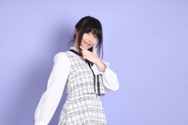 Mor arka planda duran beyaz elbiseli Asyalı genç kız..