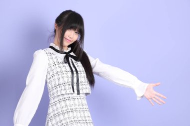 Mor arka planda duran beyaz elbiseli Asyalı genç kız..