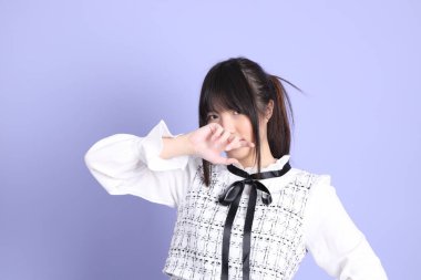 Mor arka planda duran beyaz elbiseli Asyalı genç kız..