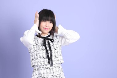 Mor arka planda duran beyaz elbiseli Asyalı genç kız..