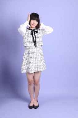 Mor arka planda duran beyaz elbiseli Asyalı genç kız..