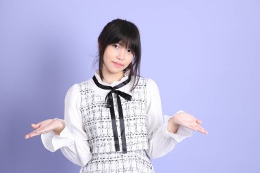 Mor arka planda duran beyaz elbiseli Asyalı genç kız..