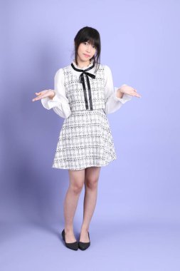 Mor arka planda duran beyaz elbiseli Asyalı genç kız..