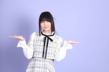 Mor arka planda duran beyaz elbiseli Asyalı genç kız..