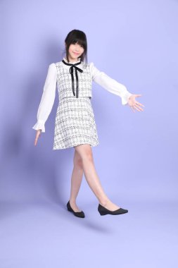 Mor arka planda duran beyaz elbiseli Asyalı genç kız..