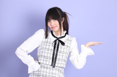 Mor arka planda duran beyaz elbiseli Asyalı genç kız..