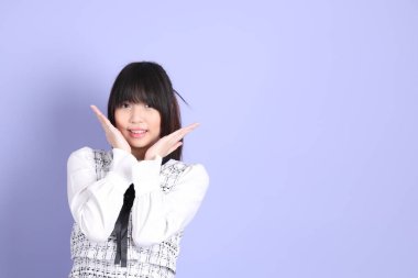 Mor arka planda duran beyaz elbiseli Asyalı genç kız..