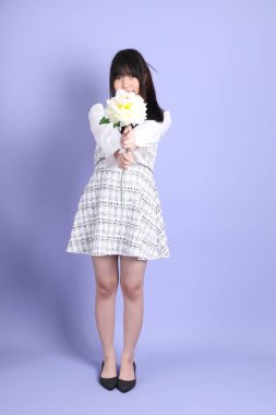 Mor arka planda duran beyaz elbiseli Asyalı genç kız..