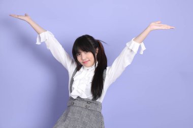 Mor arka planda oturan beyaz giysili tatlı Asyalı kız.