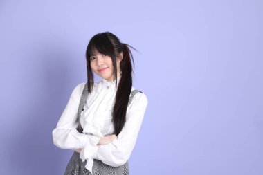 Mor arka planda duran beyaz giysili tatlı Asyalı kız.