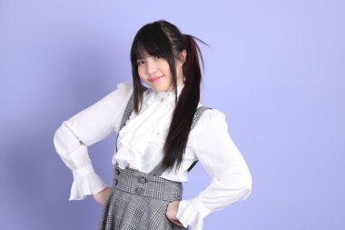 Mor arka planda duran beyaz giysili tatlı Asyalı kız.