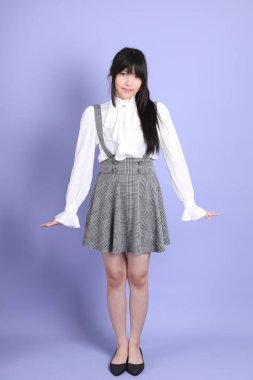 Mor arka planda duran beyaz giysili tatlı Asyalı kız.