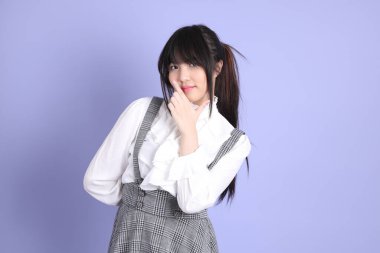 Mor arka planda duran beyaz giysili tatlı Asyalı kız.