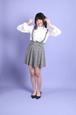 Mor arka planda duran beyaz giysili tatlı Asyalı kız.