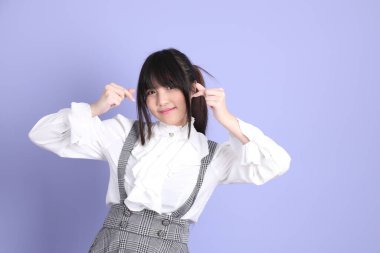 Mor arka planda duran beyaz giysili tatlı Asyalı kız.