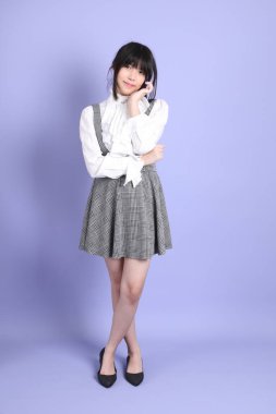 Mor arka planda duran beyaz giysili tatlı Asyalı kız.