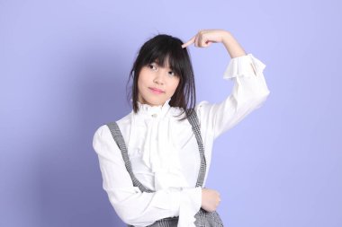 Mor arka planda duran beyaz giysili tatlı Asyalı kız.