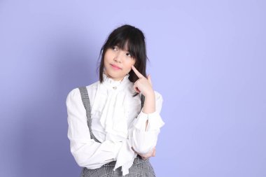 Mor arka planda duran beyaz giysili tatlı Asyalı kız.